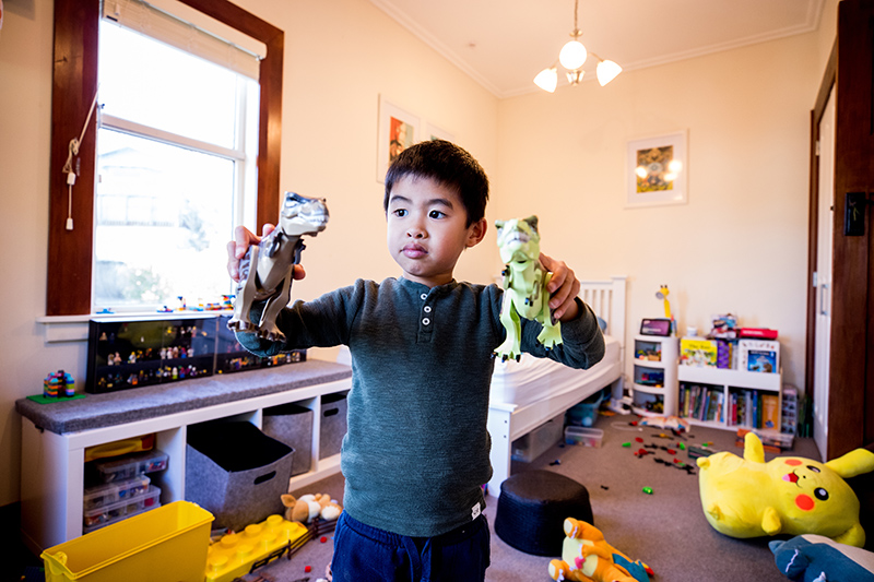 A young boy plays with his toy dinosaurs.